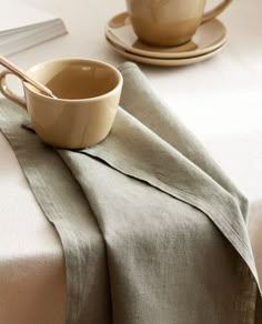 two cups and saucers sitting on top of a white table cloth covered placemat