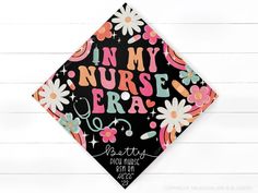 a graduation cap with the words in my nurse era printed on it and daisies