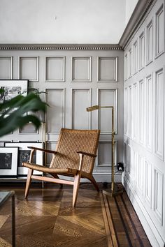 a chair sitting on top of a hard wood floor next to a wall with white paneling