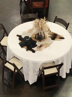 a white table with chairs and a hat on it's head sits in the middle of a room