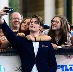 a man taking a selfie with his friends at an event in front of a crowd