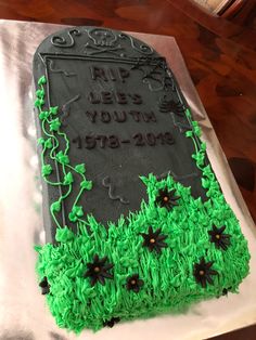 a cake with green frosting and black icing on top of a silver sheet