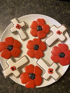 decorated cookies arranged in the shape of crosses and flowers on a white plate with black dots