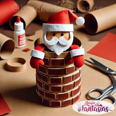 paper mache santa claus sitting on top of a brick chimney surrounded by crafting supplies