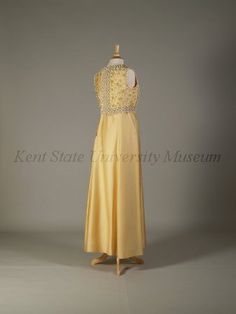 Pierre Balmain Haute Couture evening dress from French 1960-1970. Made from yellow silk satin peau de soie ground, yellow dome caps, embroidered  embroidery with bead, pearl, rhinestones, cream cord loops, white plastic lilies flower, light yellow braid trim,  and dome lucite button. Sleeveless floor length A line gown in scoop necked style.#Balmain #HauteCouture #Vintage #Fashion House of Balmain.