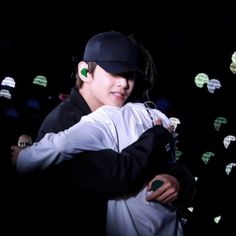 a man and woman hugging each other in front of many green lights on the wall