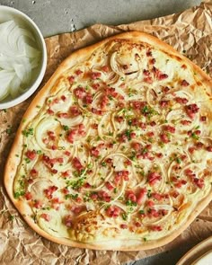 a pizza sitting on top of a piece of wax paper next to a bowl of onion rings