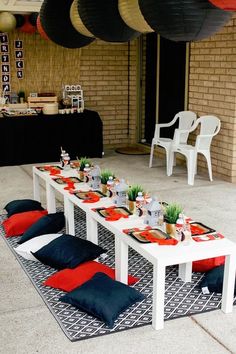 a table set up for a party with red and black pillows on the rugs