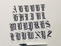 an old english type of calligraphy is shown with a pen on top of it