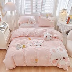 a bed with pink comforter and pillows in a room next to a white window