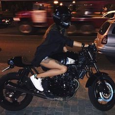 a woman sitting on a motorcycle in the street at night with her legs spread out