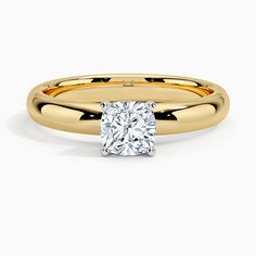 a yellow gold engagement ring with a cushion cut diamond in the center, on a white background