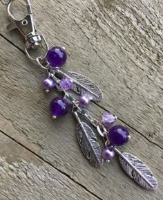 a key chain with purple beads and leaves on it