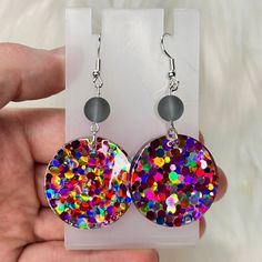 These handmade resin statement earrings add a playful touch to any outfit with their vibrant color pop of pink, yellow, and purple. Each earring features a unique glass bead, making them one-of-a-kind pieces. Elevate your style with these colorful and chic earrings. Glass bead color will vary ❤️ Nickle Free  Each pair of earrings is unique and handmade. Multicolor Hypoallergenic Jewelry For Party, Multicolor Hypoallergenic Party Jewelry, Hypoallergenic Multicolor Earrings For Parties, Fun Purple Jewelry For Party, Colorful Party Earrings With Ear Wire, Fun Purple Party Jewelry, Circle Earrings With Ear Wire For Party, Playful Purple Jewelry For Party, Purple Fun Jewelry For Party