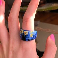 a woman's hand with a ring on it that has flowers painted on it