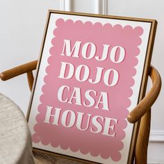 a pink sign that says mojo dojo casa house in white on a wooden chair