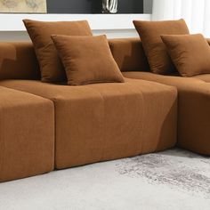 a brown couch sitting on top of a white floor next to a window with curtains