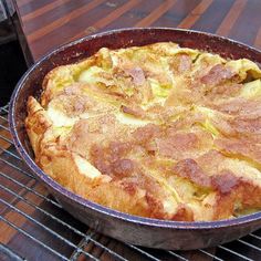 a pan filled with food sitting on top of a grill next to a bottle of wine