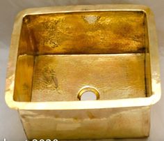 a gold square shaped sink sitting on top of a white sheet