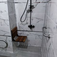 a walk in shower sitting next to a wooden bench on top of a tiled floor