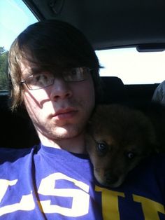 a man sitting in the back seat of a car holding a puppy