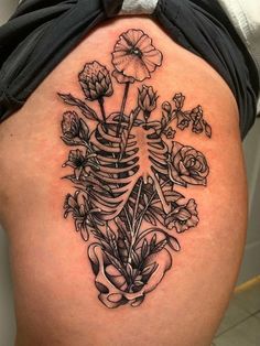 a woman's thigh with a skeleton and flowers on it