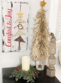 a small christmas tree sitting on top of a black table next to a white sign