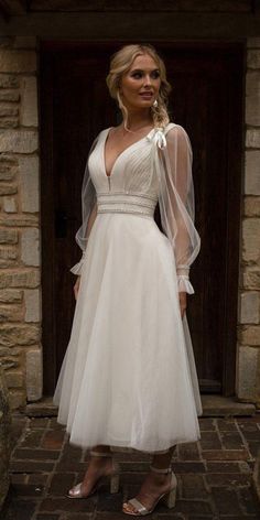 a woman in a white dress is standing outside