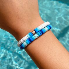 a woman's arm with two bracelets on it next to a swimming pool