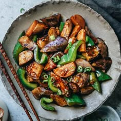 a plate filled with stir fry vegetables and chopsticks