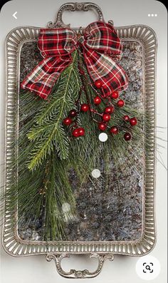 a christmas ornament hanging on the side of a wall with holly and berries