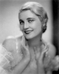 an old black and white photo of a woman with her hands on her chest smiling