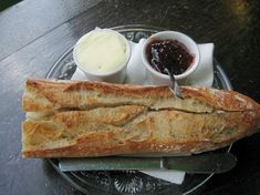 a loaf of bread sitting on top of a glass plate next to butter and jelly