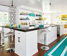 a kitchen with white cabinets and black counter tops next to a blue rug on the floor