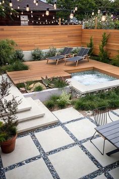 an outdoor hot tub in the middle of a patio with chairs and lights above it