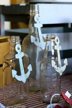 three empty bottles are sitting on a table with an anchor decal in the middle