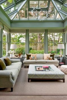 a living room filled with lots of furniture under a glass roof over a patio area