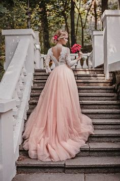 a woman in a long sleeved dress standing on some stairs with her hands behind her back