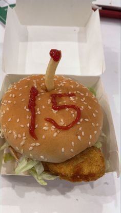 a chicken sandwich with ketchup and lettuce in a white box on a table