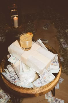 a wooden table topped with lots of money and a small glass filled with liquid sitting on top of it