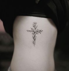 a cross tattoo on the side of a woman's stomach