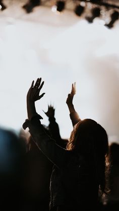 a person with their hands up in the air at a music festival or concert,