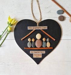 a heart shaped decoration with rocks and stones in the shape of a family's house