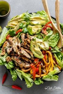 a salad with chicken, peppers and avocado on it