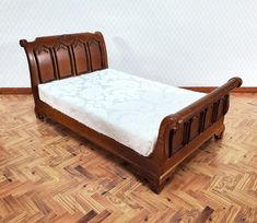 a wooden bed sitting on top of a hard wood floor next to a white wall