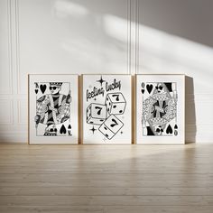 three framed playing cards sitting on top of a hard wood floor next to a white wall