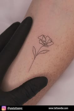 a small flower tattoo on the left arm