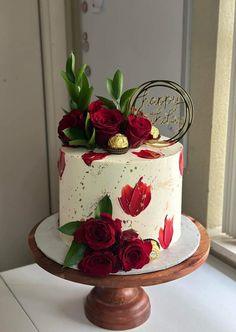 a white cake with red flowers and gold decorations