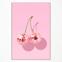 two pink cherries are hanging from a string on a pink background with the shadow of a cherry