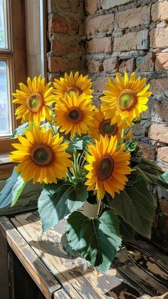 a vase filled with yellow sunflowers sitting on top of a wooden table next to a window